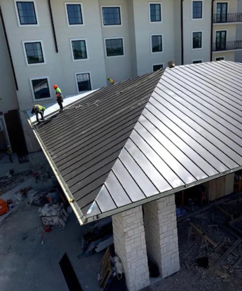 Crew installing standing seam metal roof panels on a commercial project in Smithfield